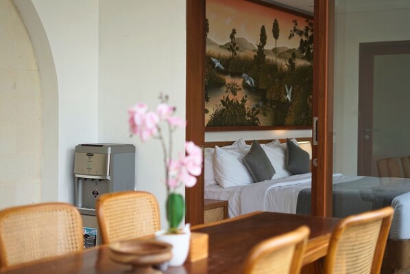 A hotel room with a bed, a desk with a computer, and a painting of birds and trees on the wall.