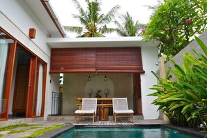 A pool area with two white wicker chairs, a wooden table, and a wooden ceiling. - Anara Villa Ubud (Mas)