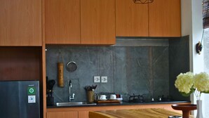 Una cucina con mobili in legno, una parete di fondo in marmo, un lavello in acciaio inossidabile e un tavolo da pranzo in legno.