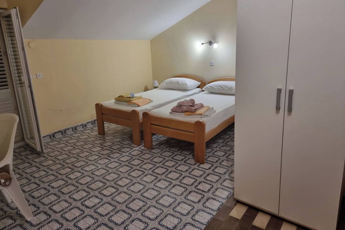 A room with two wooden beds, a wardrobe, and a patterned floor.