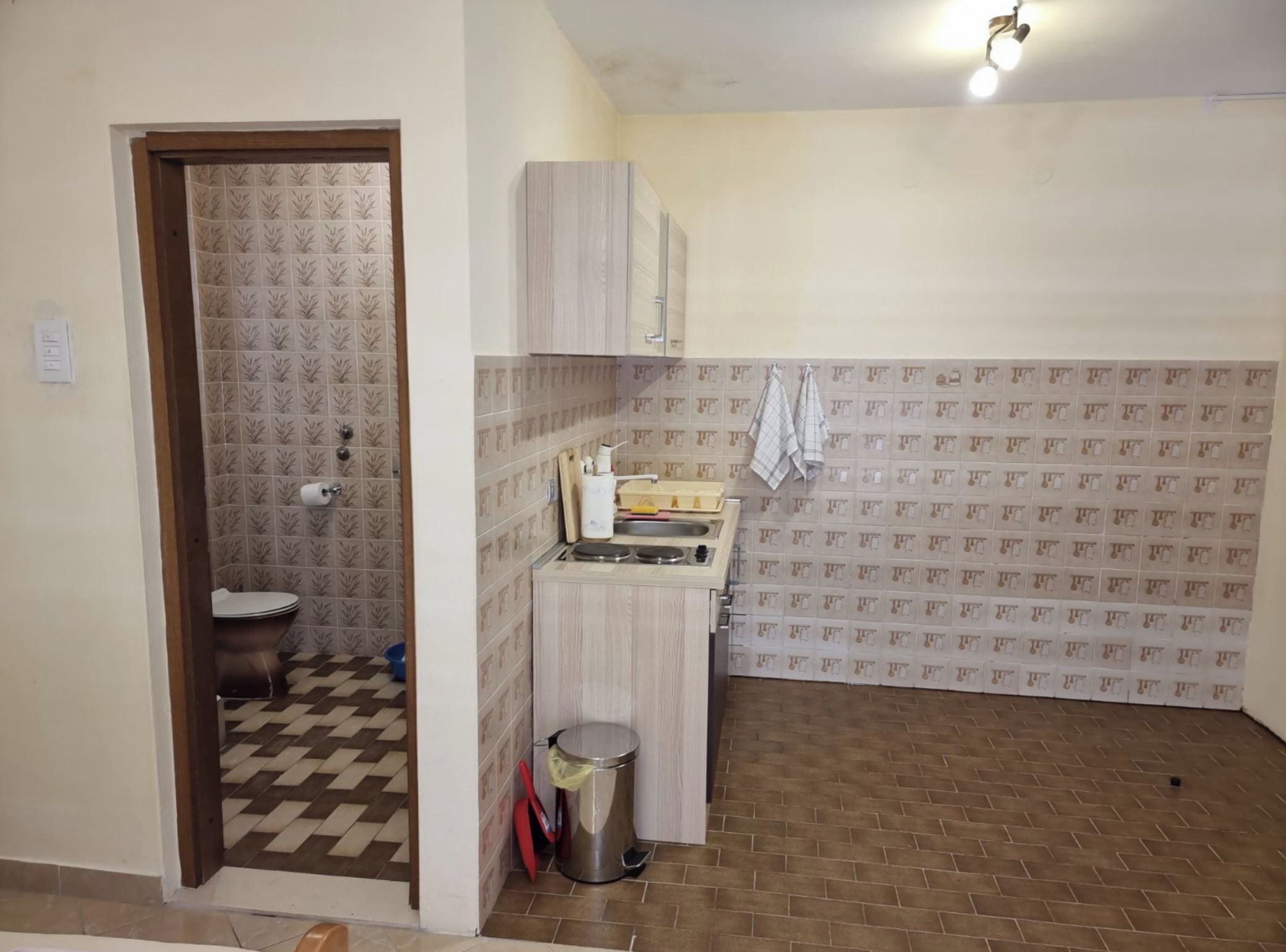 Une petite salle de bain propre, avec des toilettes, un lavabo et des murs carrelés.