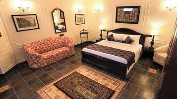 A bedroom with a bed, a sofa, a rug, and wall-mounted lamps.