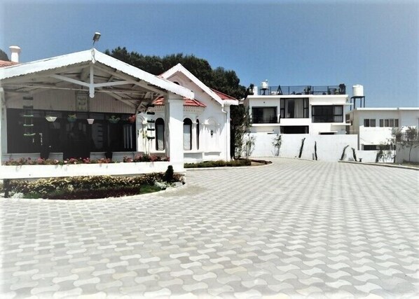 Um edifício com área externa coberta, calçada e céu claro.