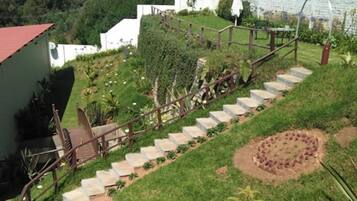 A set of outdoor stairs leading up to a building with a red roof, surrounded by greenery and a garden area.