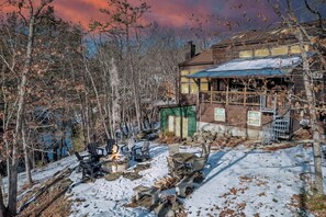 A rustic cabin with a fire pit, outdoor seating, and a snow-covered landscape. - Waterfall Views! Hot Tub, Game Room, Dog Friendly (Bushkill)
