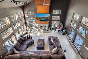 A spacious living area with a fireplace, multiple windows, and a large flat-screen TV. - Waterfall Views! Hot Tub, Game Room, Dog Friendly (Bushkill)