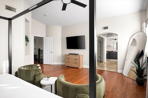 A spacious living room with a wooden floor, a flat-screen TV mounted on the wall, and a dining area with a small table and chairs. - Epic Getaway | Sport Court | Heated Pool & Slide (Scottsdale)