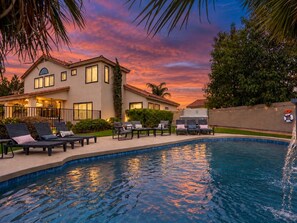 A two-story house with a swimming pool, outdoor furniture, and a sunset sky. - Epic Getaway! Pool Slide | Sportscourt | Heated Pool | Gameroom (Scottsdale)
