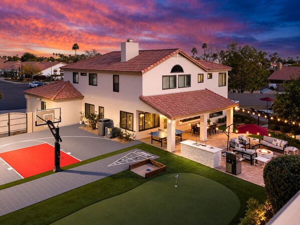 A residential property with a basketball court, outdoor seating area, and a well-maintained lawn. - Epic Getaway! Pool Slide | Sportscourt | Heated Pool | Gameroom (Scottsdale)