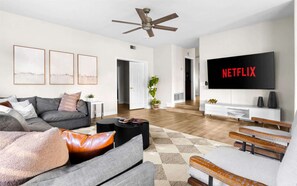 A modern living room with a grey sofa, a coffee table, and a TV displaying 'NETFLIX'. - Epic Getaway | Sport Court | Heated Pool & Slide (Scottsdale)