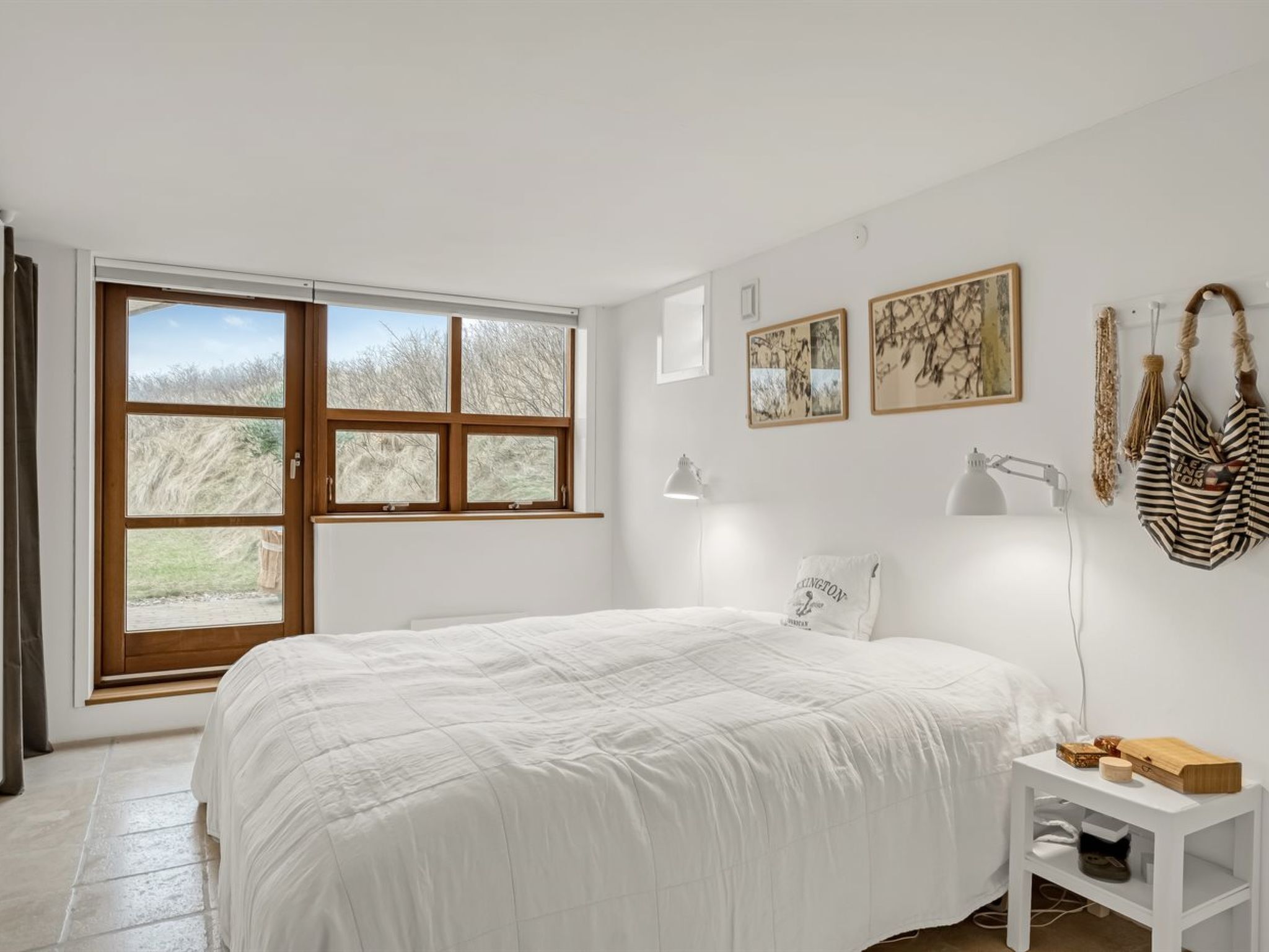 Un dormitorio con una cama grande, un escritorio con lámpara y vistas a árboles a través de una puerta corredera.