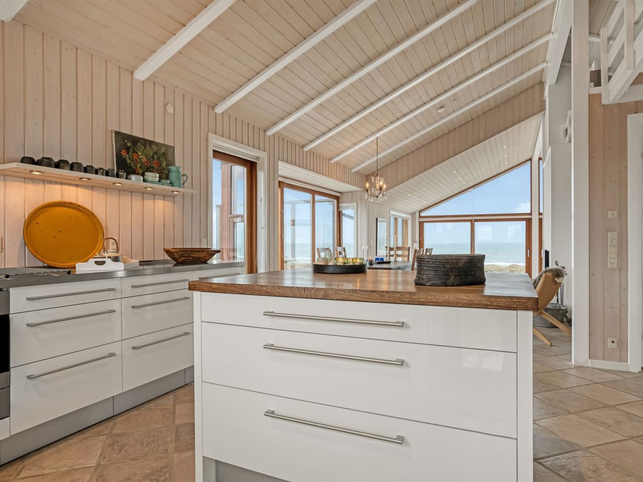 Een ruime keuken met een groot eiland, witte kasten en uitzicht op de oceaan.