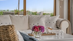 Un rincón exterior acogedor con un sofá, una mesa con vela, flores y vistas al paisaje.