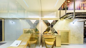 A modern hotel lobby with a wooden reception desk, a yellow chair, and a glass partition. - Xspa apartment cryptocurrency pay available (Novi Sad)