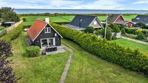 Ein Wohngebiet mit Häusern, einem grünen Rasen und Blick auf das Meer.