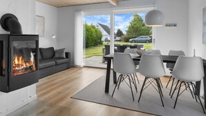 Ein modernes Wohnzimmer mit Kamin, einem Essbereich mit Stühlen und Blick ins Freie.