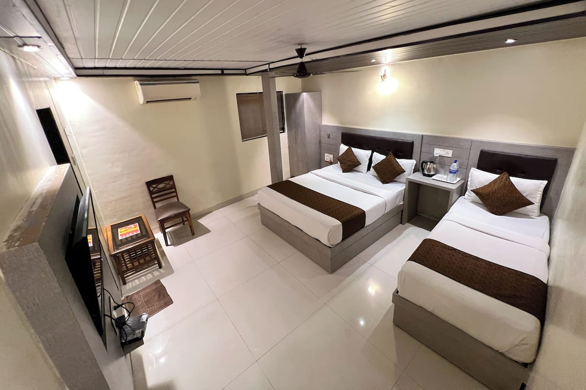 Habitación de hotel con dos camas, televisión, escritorio y silla.