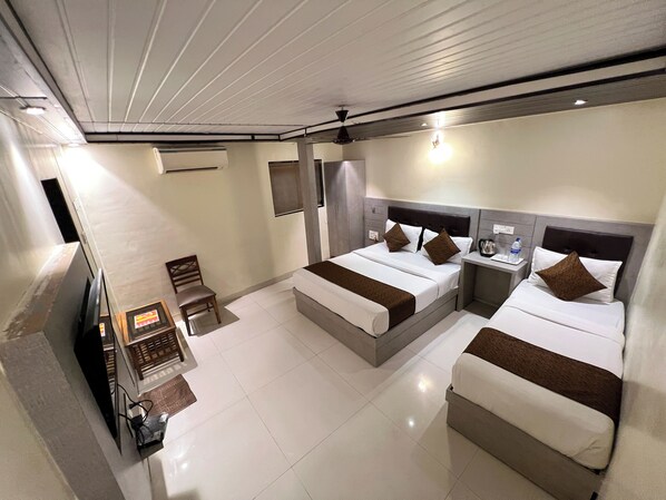 A hotel room with two beds, a TV, a desk, and a chair. - New Hotel Prince Palace (Mumbai)
