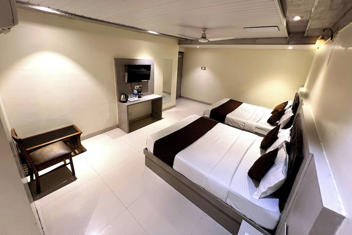 Una habitación de hotel con dos camas, un escritorio, un televisor y un ventilador de techo.