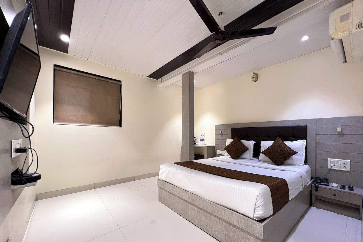 Una habitación de hotel moderna con una cama grande, una mesita de noche y un ventilador de techo.