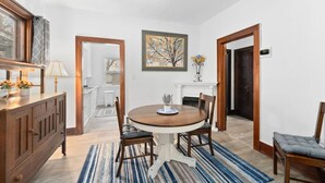 A dining area with a round table, chairs, a buffet cabinet, and a fireplace. - Charming Centrally Located Sunroom/Fireplace (Sioux Falls)