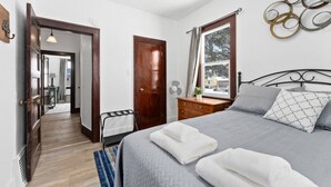 A bedroom with a bed, bedside table, and a window. - Charming Centrally Located Sunroom/Fireplace (Sioux Falls)