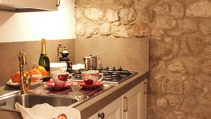 A kitchen with white cabinets, a stone wall, a gas stove, and a sink. - Residenza dei TOLOMEI Confort Relax Centro Storico  (Polcenigo)