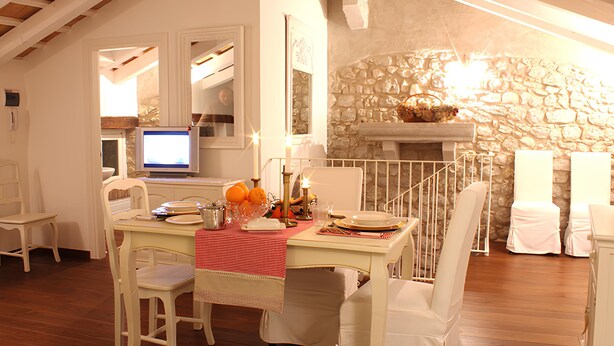 A dining area with a stone wall, a fireplace, and a television in the background. - Residenza dei TOLOMEI Confort Relax Centro Storico  (Polcenigo)