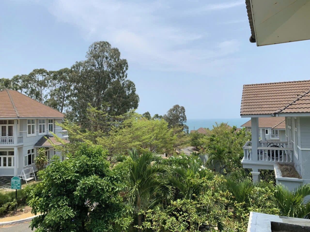 Un quartier résidentiel situé sur la côte, avec des maisons, une végétation luxuriante et une vue dégagée sur la mer.