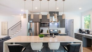 Una cocina moderna con una isla central, electrodomésticos de acero inoxidable e iluminación colgante.