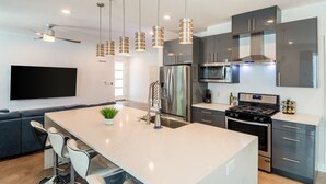 Una cocina moderna con una isla central, electrodomésticos de acero inoxidable e iluminación colgante.