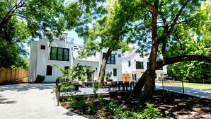 Un edificio moderno con techo plano, amplios ventanales y un patio empedrado con mobiliario exterior.
