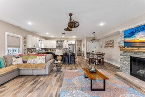 A spacious living area with a large sectional sofa, a dining table, and a fireplace. - New 3BR Condo with Rooftop Walk to Beach Boardwalk (Wildwood)
