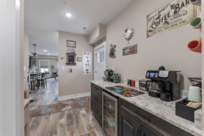 A kitchen with a coffee station, a dining area, and a hallway leading to another room. - New 3BR Condo with Rooftop Walk to Beach Boardwalk (Wildwood)
