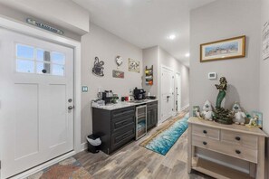 A modern kitchen with a built-in island, a coffee station, and a decorative wall with coffee-themed items. - New 3BR Condo with Rooftop Walk to Beach Boardwalk (Wildwood)