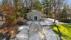 A small, single-story building with a garage door, surrounded by trees and a snow-covered path. - Pleasant Cove | Waterfront Getaway with Fire Pit, Deck, and Lake Views (Mooresville)