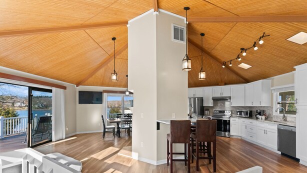 A spacious kitchen with wooden flooring, white cabinets, and pendant lighting. - Pleasant Cove | Waterfront Getaway with Fire Pit, Deck, and Lake Views (Mooresville)