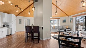 A spacious kitchen with wooden flooring, white cabinets, and pendant lighting. - Pleasant Cove | Waterfront Getaway with Fire Pit, Deck, and Lake Views (Mooresville)