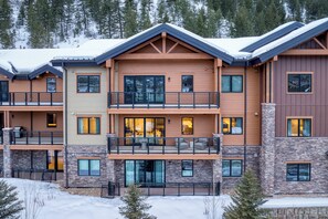 A multi-story hotel with a stone facade, balconies, and large windows.