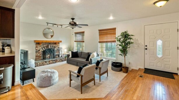 A spacious living room with a fireplace, a ceiling fan, and a large window with blinds. - Canyon Ridge Getaway | Arcade| View | Free Massage* (Cedar Hills)