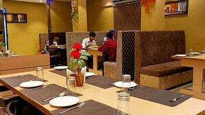 A restaurant with booths and tables, some with placemats and water glasses. - The Ganga Residency (Barh)
