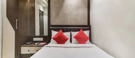 A hotel room with a bed, a dresser, a mirror, and a large wall-mounted artwork.