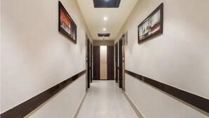 A hallway with a polished floor, framed artwork on the walls, and doors leading to rooms. - The Ganga Residency (Barh)