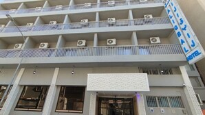 Un hôtel à plusieurs étages, doté de balcons, de climatiseurs et d’une enseigne indiquant qu’il s’agit d’un hôtel.