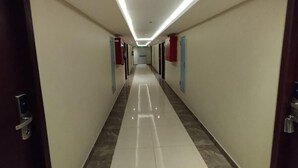Un long couloir étroit, doté d’un sol carrelé brillant et d’un plafond éclairé par des luminaires linéaires.