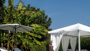 Piscina azul límpida com espreguiçadeiras e toldo.