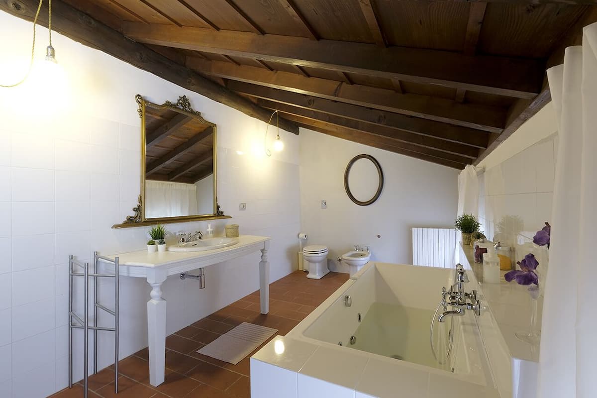 A bathroom with a bathtub, two sinks, a toilet, and a large mirror.