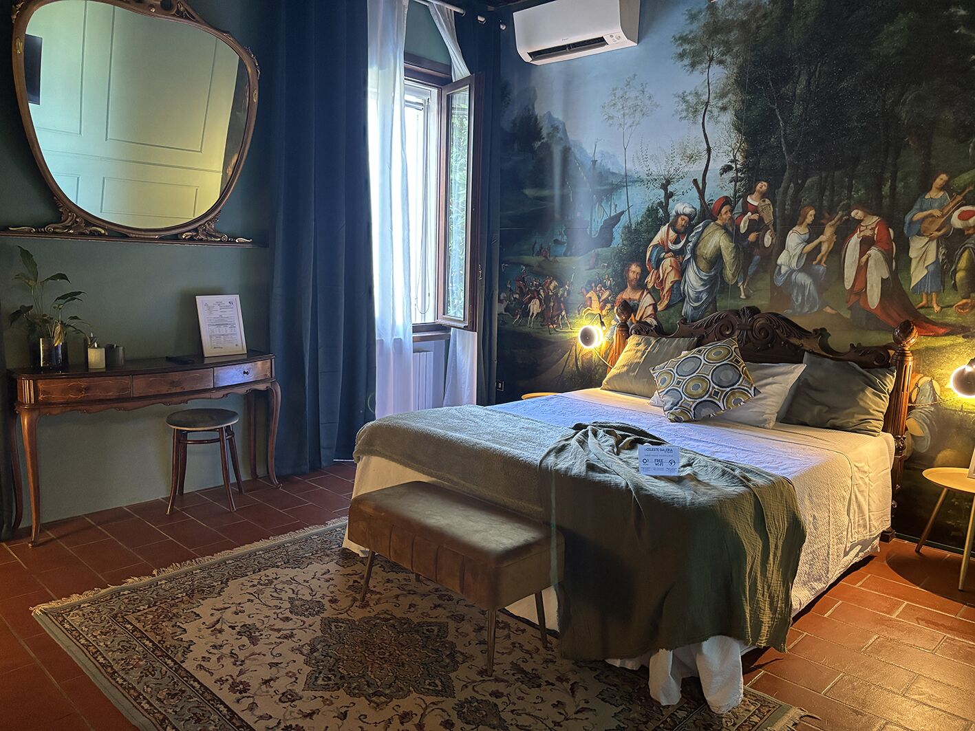 A bedroom with a bed, a desk, a chair, a large mirror, and a mural on the wall.