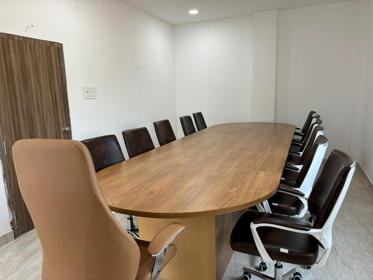 Una sala de conferencias con una gran mesa de madera rodeada de sillas de cuero.
