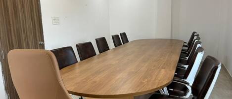 Una sala de conferencias con una gran mesa de madera rodeada de sillas de cuero.